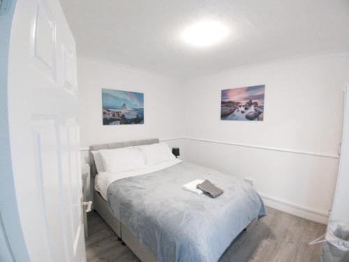 a bedroom with a bed and two pictures on the wall at Exquisite Two Bed Apartment in Grays - Free Wi-Fi and Netflix in Stifford