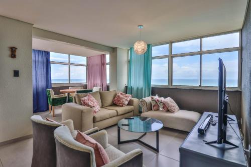 sala de estar con sofá, sillas y TV en Shangri-La Self Catering Holiday Apartment, en Kingsborough