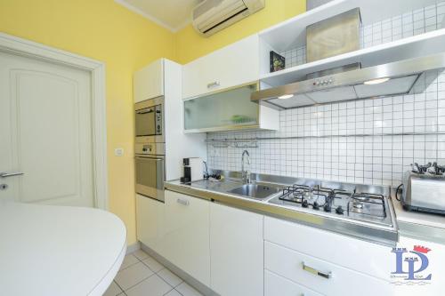 una cocina con armarios blancos y fregadero en DesenzanoLoft Villa Palm Garda Beach, with garden, barbecue and pool, en Desenzano del Garda