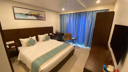 a bedroom with a bed and a window with blue curtains at The Zen Park Coimbatore in Coimbatore