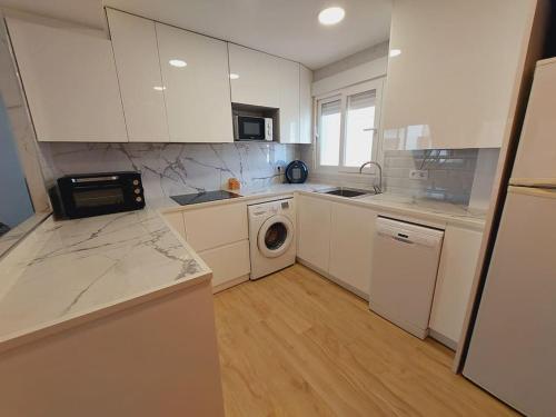 a kitchen with white cabinets and a washing machine at CalafellBeach.SeaViews,New in Calafell