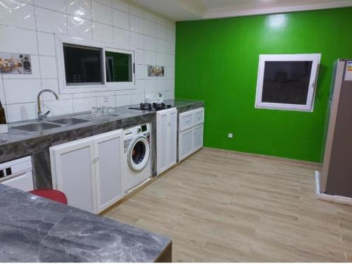 - une cuisine avec un mur vert et un lave-linge dans l'établissement Villa Eloy, à Lomé