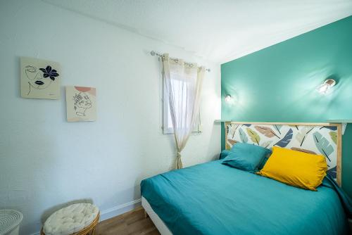 a bedroom with a blue bed and a window at Perla - Climatisée et proche plage in Canet-en-Roussillon