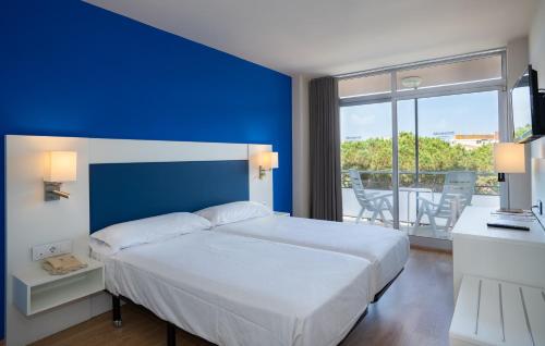 a bedroom with a white bed and a blue wall at Medplaya Hotel Monterrey in Platja d'Aro