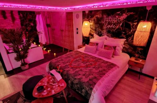 - une chambre avec un grand lit et un éclairage rose dans l'établissement Loveroom Jungle Love Proche Disneyland, à Serris
