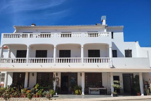 een groot wit gebouw met een balkon erboven bij Guesthouse A Lareira in Aljezur