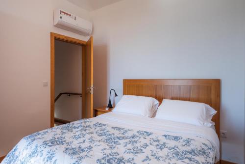 a bedroom with a bed with a blue and white blanket at Tranquilidade in Estreito da Calheta
