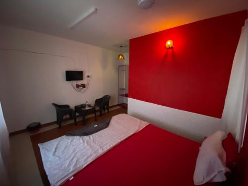 HANGOUT BEACH STAY في مهاباليبورام: غرفة نوم بجدار احمر وسرير بكراسي