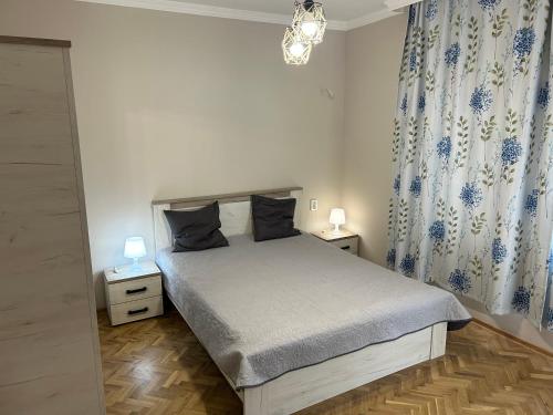 1 dormitorio con 1 cama con 2 mesitas de noche y 2 lámparas en Niya Apartment Bourgas, en Burgas