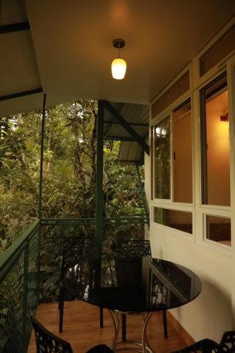 a patio with a table and chairs on a balcony at SpiceBuds FarmStay - Ramakkalmedu in Idukki