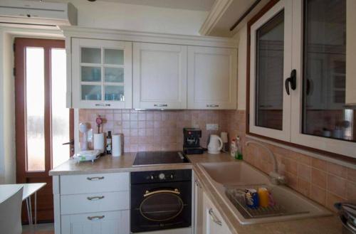 a kitchen with white cabinets and a black stove at Malvazios Villas #4 in Gythio