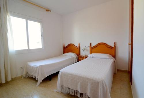 two beds in a white room with a window at Rambla Mallols 29 in L'Escala