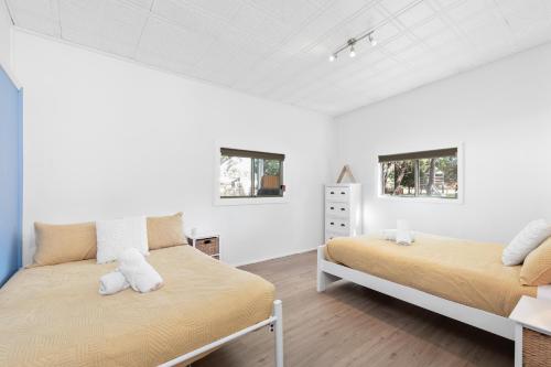 a bedroom with two beds and two windows at Abode Callala Beach Jervis Bay - 100m to Beach! in Callala Beach