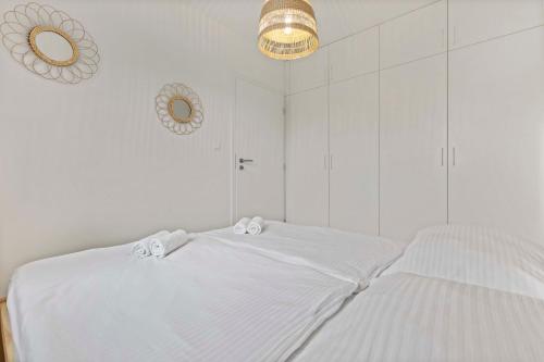 a white bedroom with two white beds and a chandelier at LAM Boho - AC - BALCONY in Bratislava