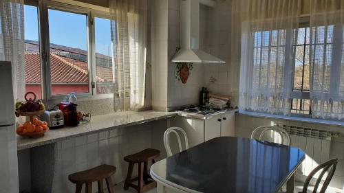 una cocina con mesa y algunas sillas y ventanas en Casa Peña Sierra de Francia, en Aldeanueva de la Sierra