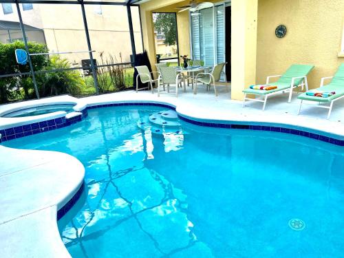 a swimming pool with chairs and a table in a house at Cozy Villa With South Facing Pool in Davenport