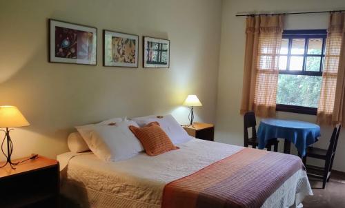 um quarto com uma cama, uma mesa e uma janela em Pousada Caminho da Serra em São Roque de Minas