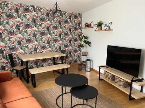 a living room with a couch and a table and a tv at Apartamento en palmeira - Colores del Barbanza Naranja in Ribeira