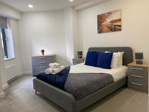 a bedroom with a large bed with blue pillows at Snapos Apartments - Platform A in Bedford