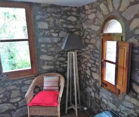 a room with a chair and a lamp and windows at Hostal La vall in Sant Pau de Segúries