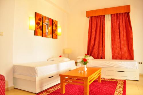 Cette chambre comprend 2 lits et une table. dans l'établissement Royal Lido Resort & Spa, à El Fehri