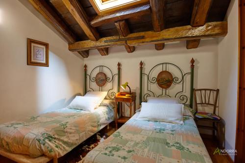 a bedroom with two beds and a wooden ceiling at Chalet Font in Soldeu
