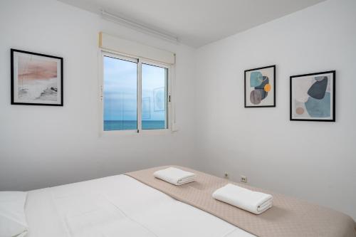 a white bedroom with a bed and a window at Seaview terrace with pool in Carvajal Ref 103 in Torremuelle