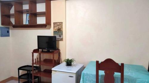 CORALYN'S PLACE standard room في بوراكاي: غرفة صغيرة مع تلفزيون وطاولة مع جهاز تلفاز
