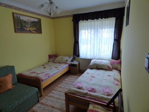 Habitación pequeña con 2 camas y ventana en Kovács Vendégház, en Zalaegerszeg