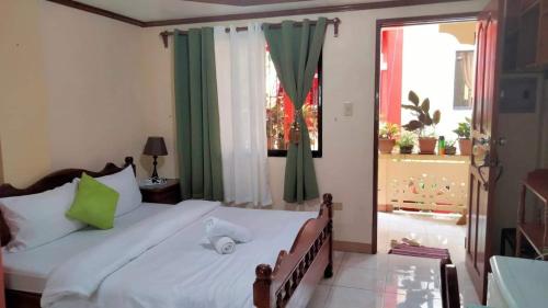 a bedroom with a bed with white sheets and green curtains at CORALYN'S PLACE standard room in Boracay