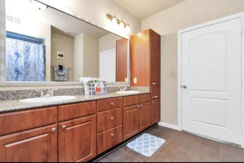 baño con 2 lavabos y espejo grande en Modern Condo near Texas Medical Center w Free Parking en Houston