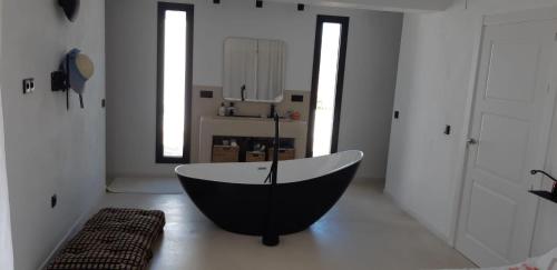 Habitación con baño con bañera en blanco y negro. en Casa Padel El Perello, en Perelló