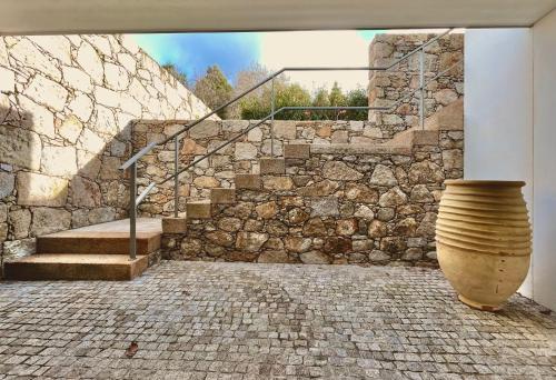 un escalier en pierre avec un vase en face d'un mur en pierre dans l'établissement Casa das Bolotas, à Viana do Castelo