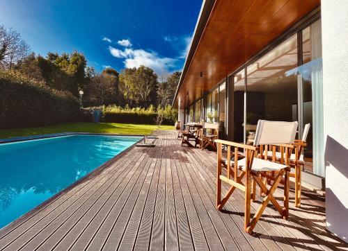 une terrasse en bois avec des chaises à côté de la piscine dans l'établissement Casa das Bolotas, à Viana do Castelo