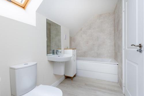 La salle de bains blanche est pourvue d'un lavabo et de toilettes. dans l'établissement Wakefield 4 Bed - Parking, Self Check-in, Fast WiFi, Near Centre, Motorway Access - Contractors, Families, Long Stays, à Wakefield