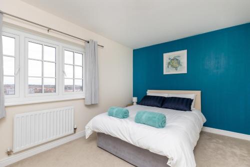 1 dormitorio con paredes azules y 1 cama con 2 almohadas en Wakefield 4 Bed - Parking, Self Check-in, Fast WiFi, Near Centre, Motorway Access - Contractors, Families, Long Stays, en Wakefield