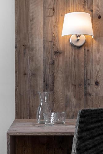 a vase and glasses on a wooden table with a lamp at Hotel Krondlhof in Brunico