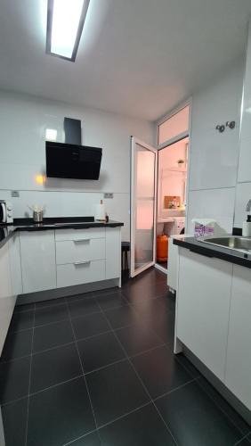 a kitchen with white cabinets and a black tile floor at Vacacional Buyma - Parking privado -GRATUITO- in Málaga