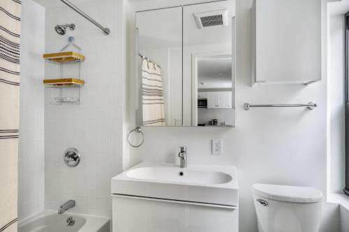 a white bathroom with a sink and a mirror at Downtown Brooklyn 2BR w WD nr Barclays Center NYC-657 in Brooklyn