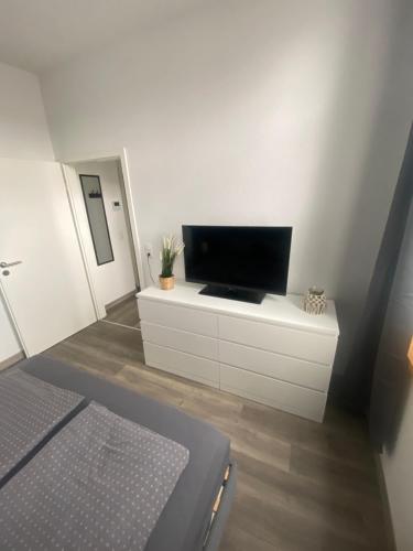 ヴィルヘルムスハーフェンにあるFeWo Muschelのベッドルーム(白いドレッサーの上にテレビ付)