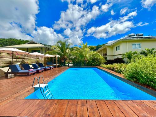 a swimming pool on a deck with chairs and a house at The Seaboards Apartments Seychelles in Mahe