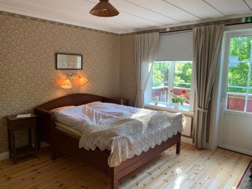 a bedroom with a bed with a white comforter and two windows at Villa Skuleskogen in Docksta