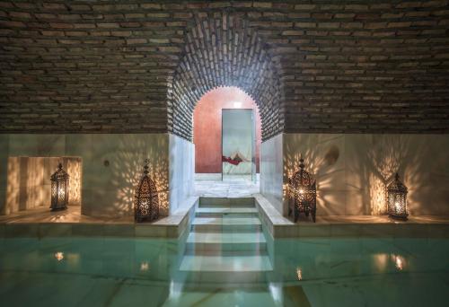 Habitación con piscina y pared de ladrillo en RIAD MEDINA MUDEJAR BAÑOS ARABES en Toledo