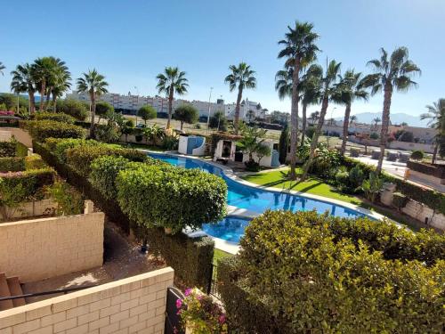 a view of a swimming pool with palm trees and bushes at Casa Verso Vera Playa in Vera