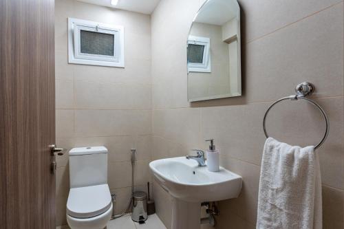 ein Badezimmer mit einem Waschbecken, einem WC und einem Spiegel in der Unterkunft Celeste 3-Bedroom Apartment in Larnaca in Larnaka