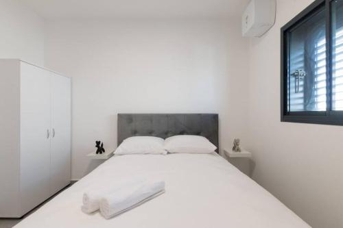 een witte slaapkamer met een groot wit bed met 2 kussens bij O&O Group - Luxury APT/3 BR/New Tower/Parking in Or Yehuda