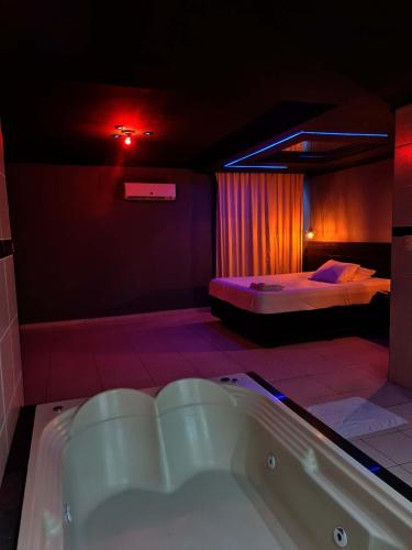 a bathroom with a tub and a bedroom with two beds at Gran Motel in Taguatinga