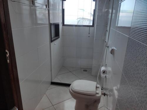 a white bathroom with a toilet and a shower at Casa Vista do Mar, praia e piscina in Vila Velha
