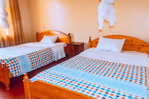a bedroom with two beds with blue and white sheets at MOUCECORE in Kigali