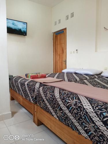una camera da letto con due letti e una TV a parete di Losmen Fadel Malioboro Jogja a Yogyakarta
